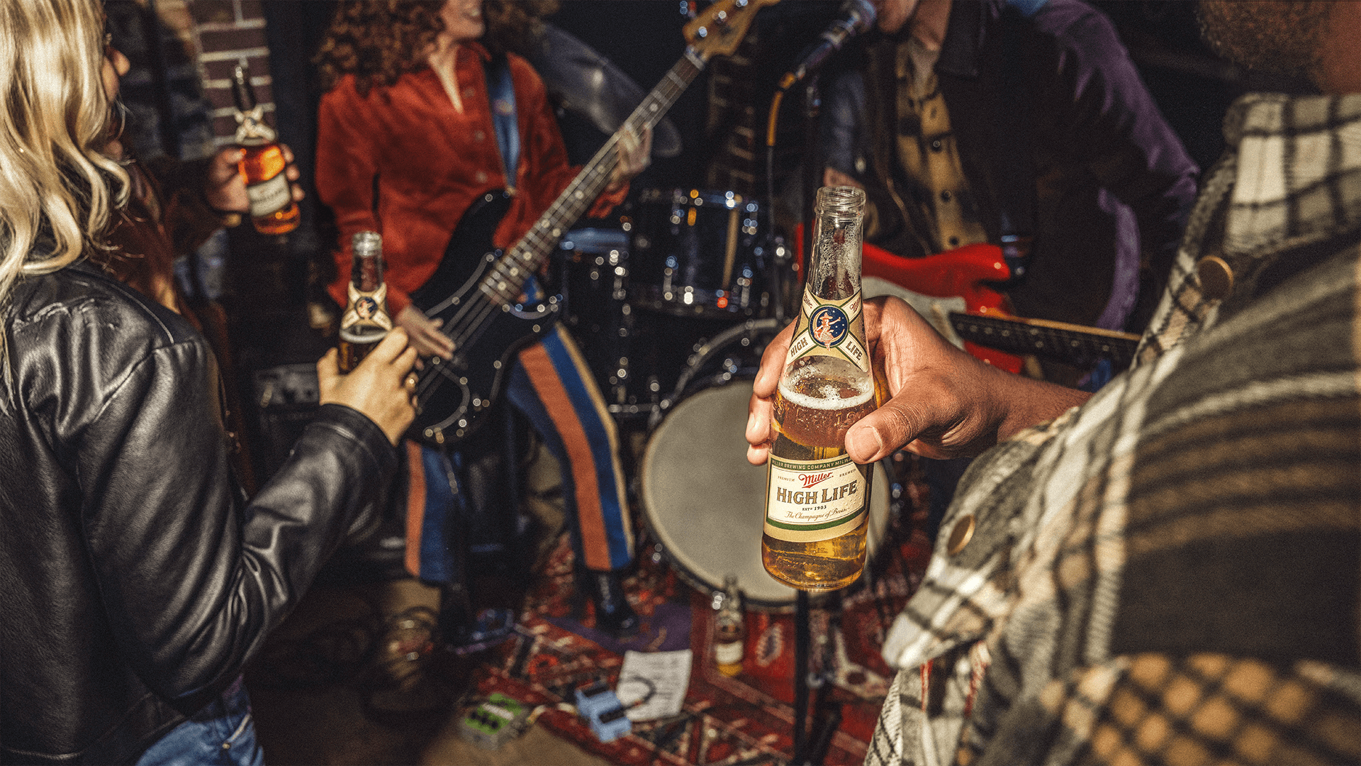 Person holding beer while band plays in the background